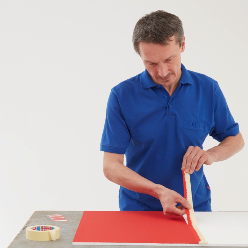 Odrywanie taśmy maskującej przez pracownika papierowej tesa® 4323 na powierzchnię po malowaniu.