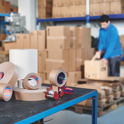 Pakowanie kartonów taśmą papierową tesa® 4713 w magazynie.