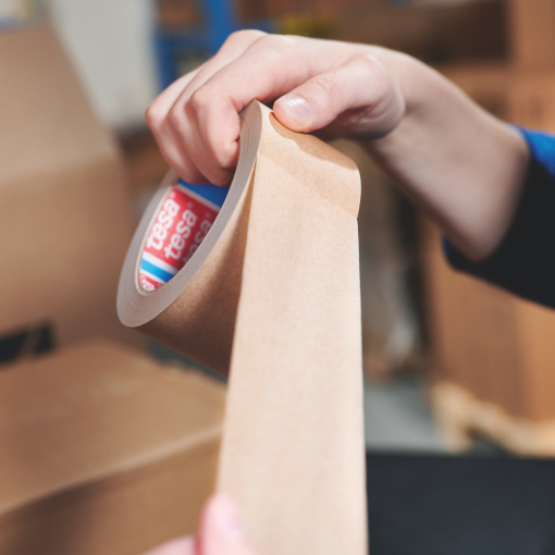 Zbliżenie na ręczne odwijanie taśmy papierowej tesa® 4713, podkreślające jej elastyczność i łatwość użycia.