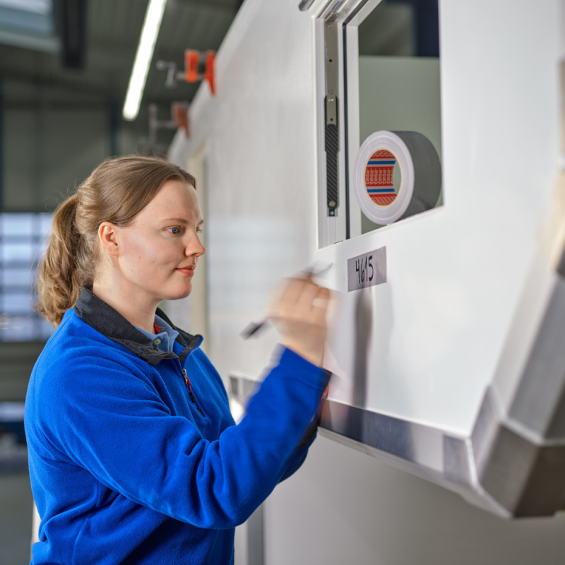 Pracownik nakleja taśmę tesa 4615 podczas prac naprawczych - szybka i łatwa aplikacja ręczna.