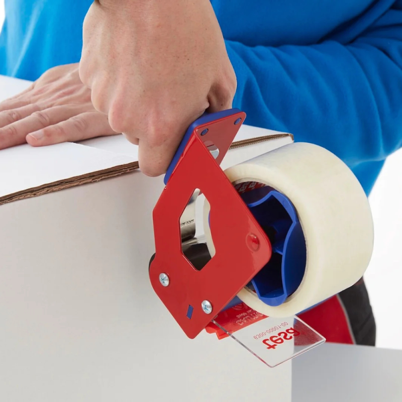 Pracownik zakleja precyzyjnie biały karton przezroczystą taśmą tesa® 4280 PV0 z użyciem ręcznego dyspenser